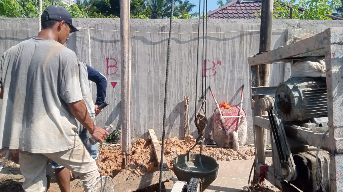 Mesin bor ringan bekerja di lahan sempit berbatas dinding, dengan titik tiang ditandai di dinding
