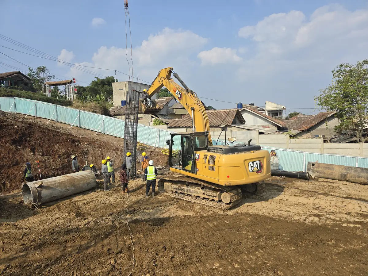 Keranjang tulangan bored pile dipasang di lubang bor, dengan casing sementara di depannya