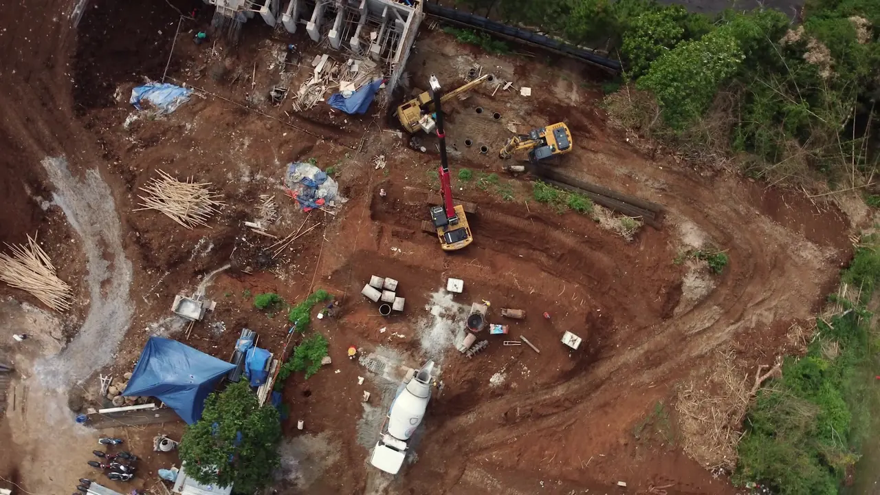 Aerial view of the working area with the drilling rig, crane and mixer truck on stepped ground