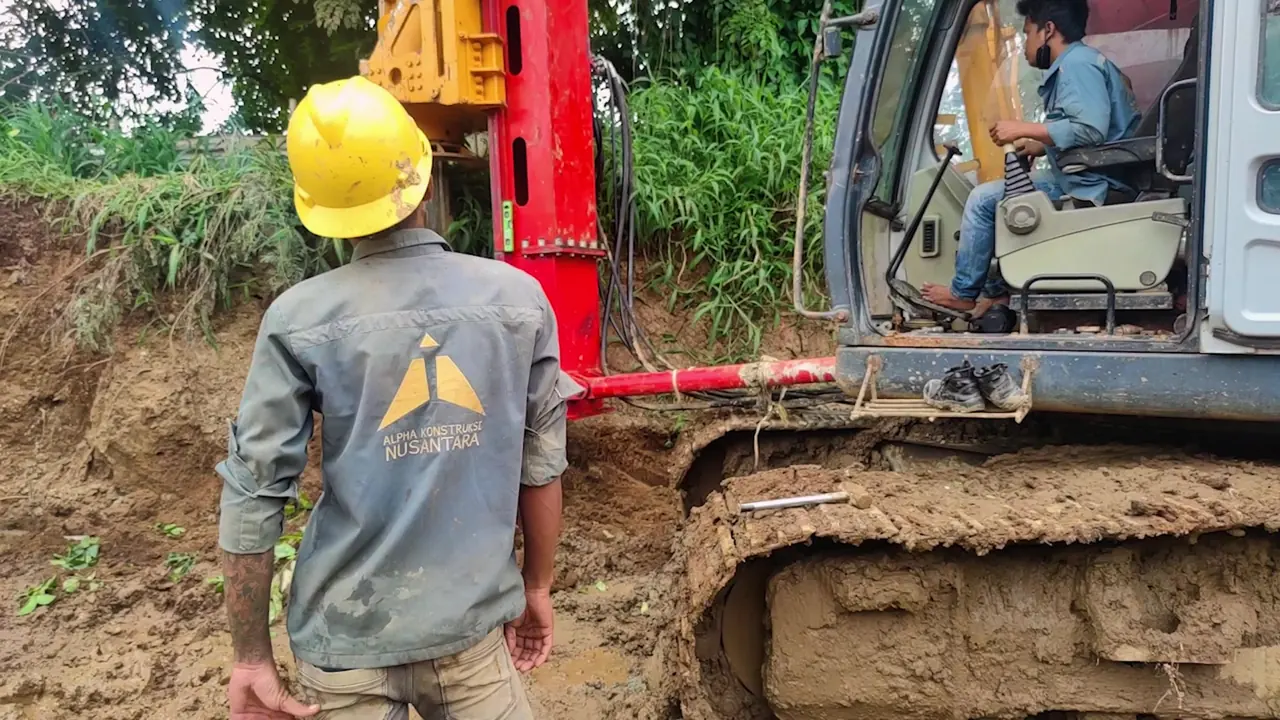 Pekerja Alpha Konstruksi mengarahkan pemasangan casing sementara operator mengendalikan alat dari kabin