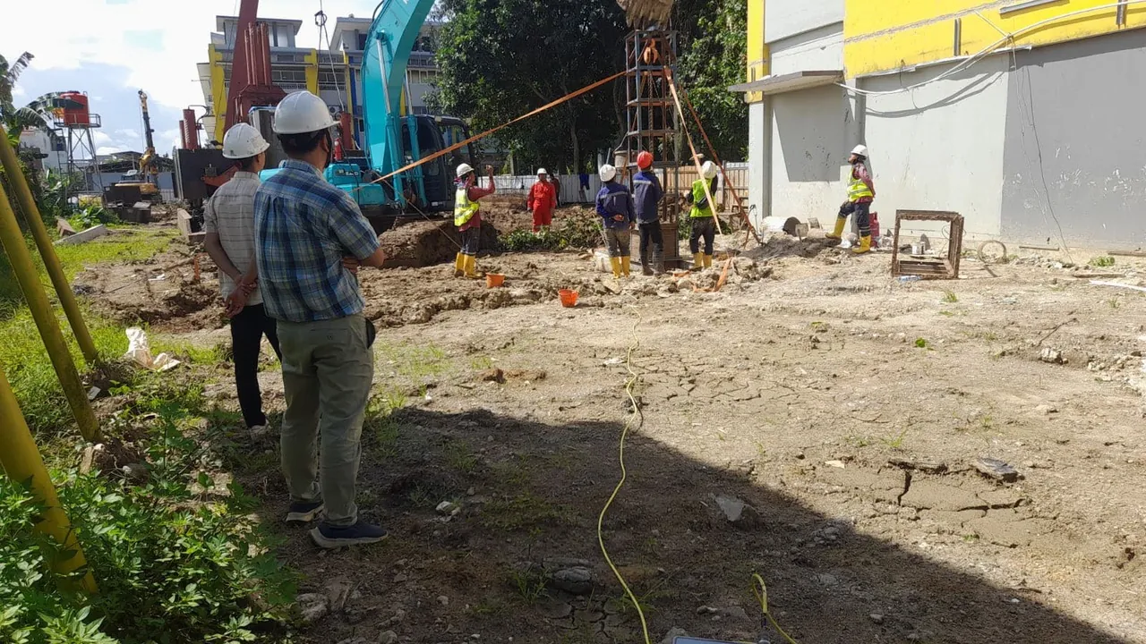 Site team and PDA testing equipment at one of the pile positions, with the drilling rig and the school building behind