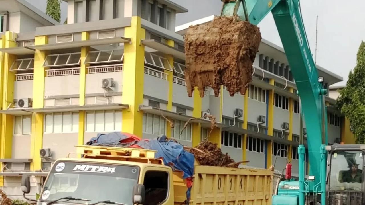 Excavator loading drilled spoil onto a truck in the grounds of the Sekolah Citra Berkat campus, Tangerang